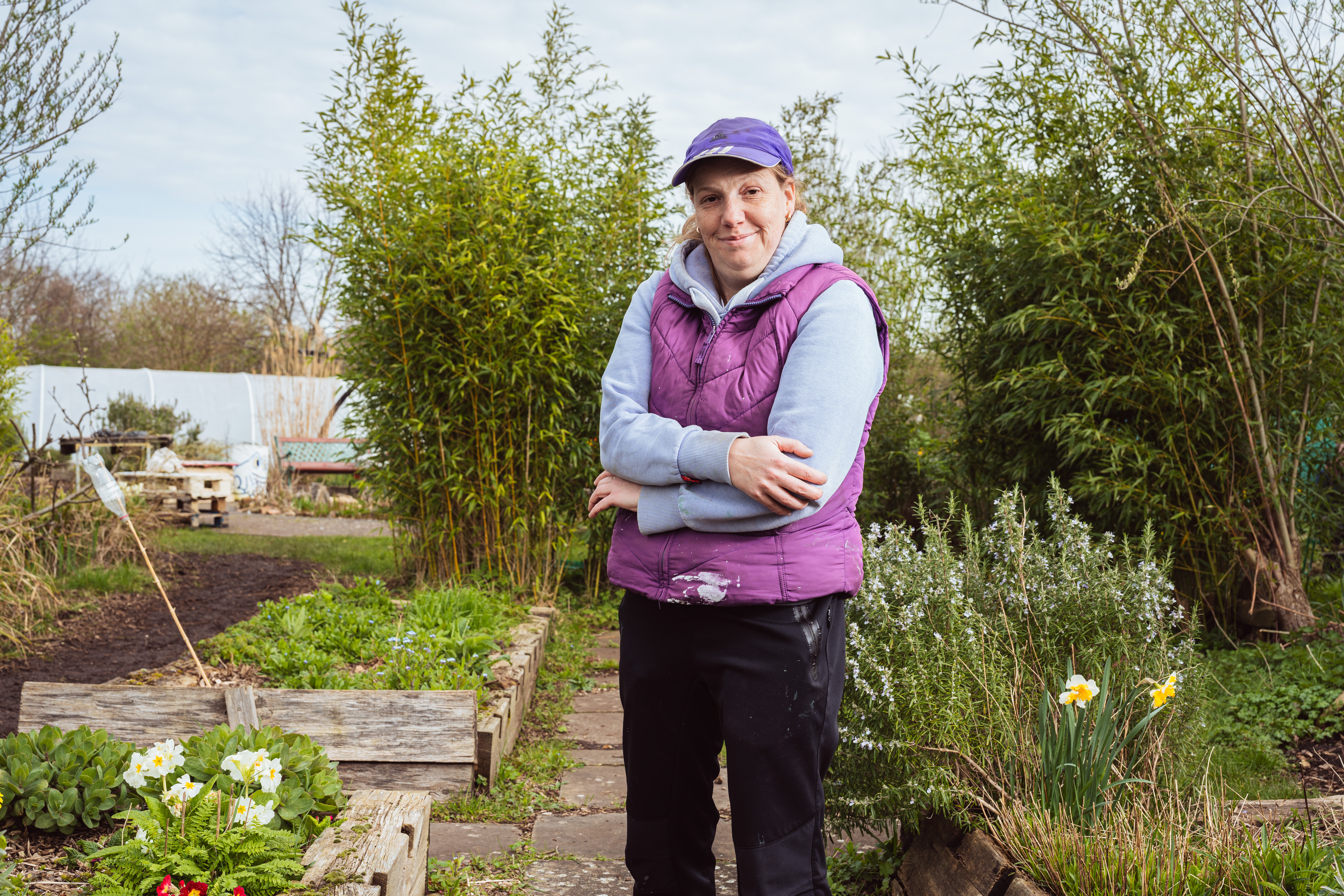 Kirsty, one of the Mencap gardeners is pictured proudly standing smiling in her allotment. 