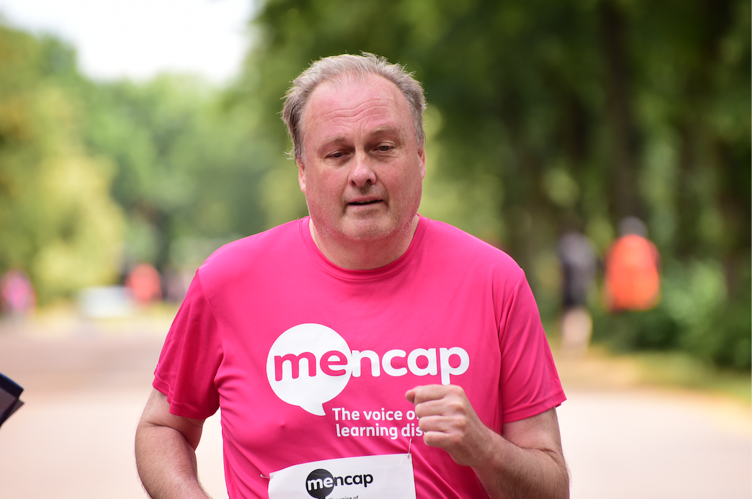 Male runner taking part in race whilst wearing a pink Mencap t-shirt.
