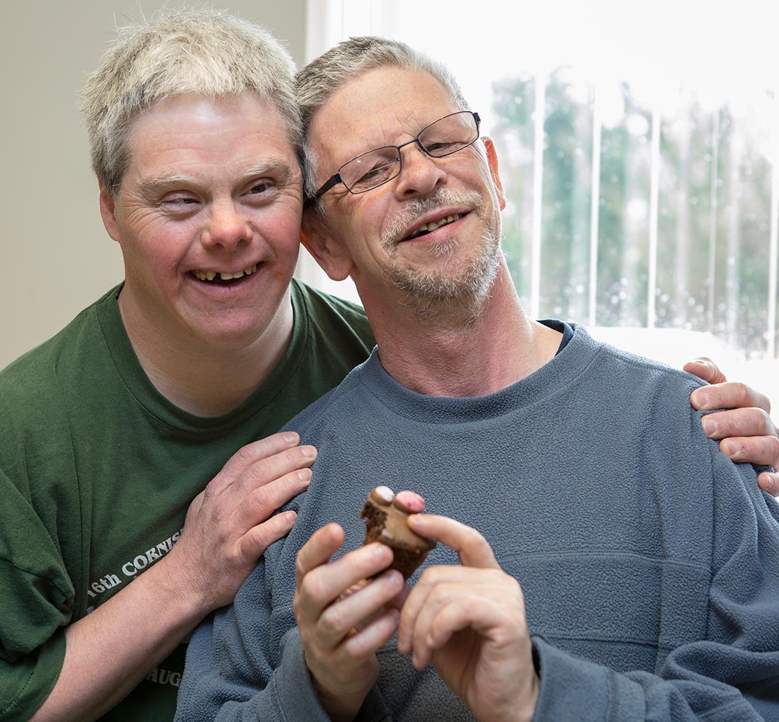 Two men smiling stood next to each other.