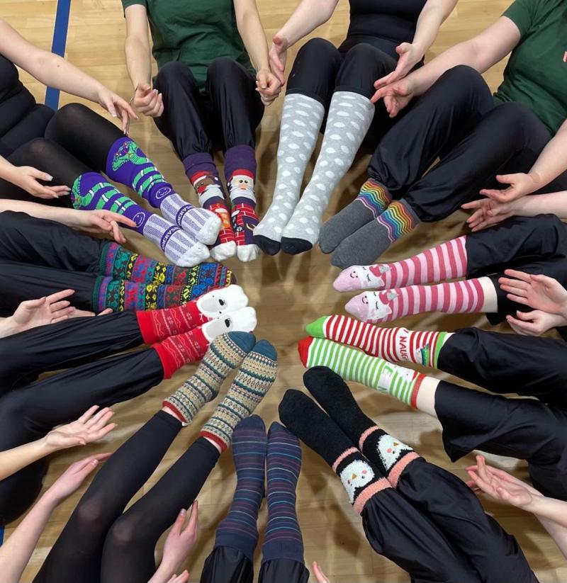 The legs and feet of 11 children sat in a circle showing their brightly coloured socks