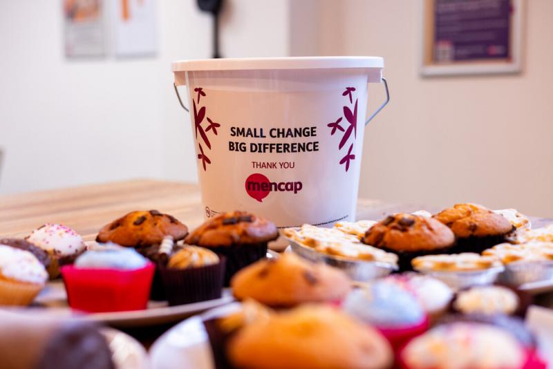 cakes on a desk with a donation bucket behind them.