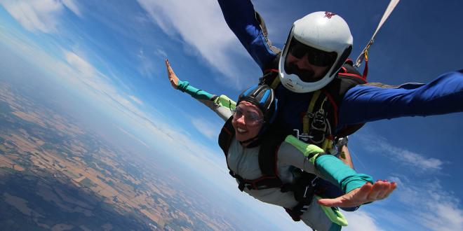 Two people strapped together taking part in a skydive.